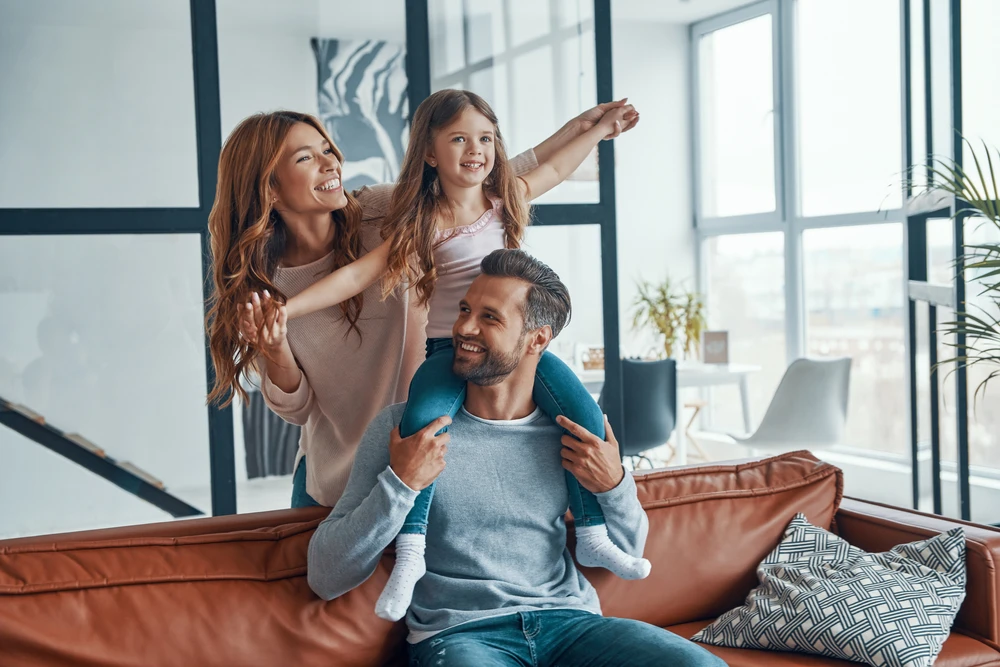 Smiling parents with their daughter sitting on her father’s shoulders